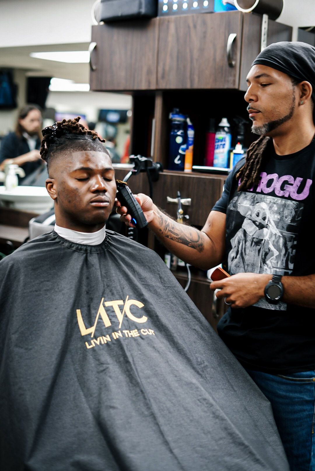 A barber running clippers along a client’s hairline in the shop.